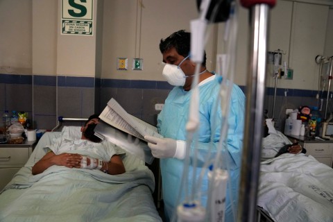 Doctor reads a report between the beds of two monkeypox patients at the Arzobispo Loayza hospital, Lima, Peru, on Tuesday